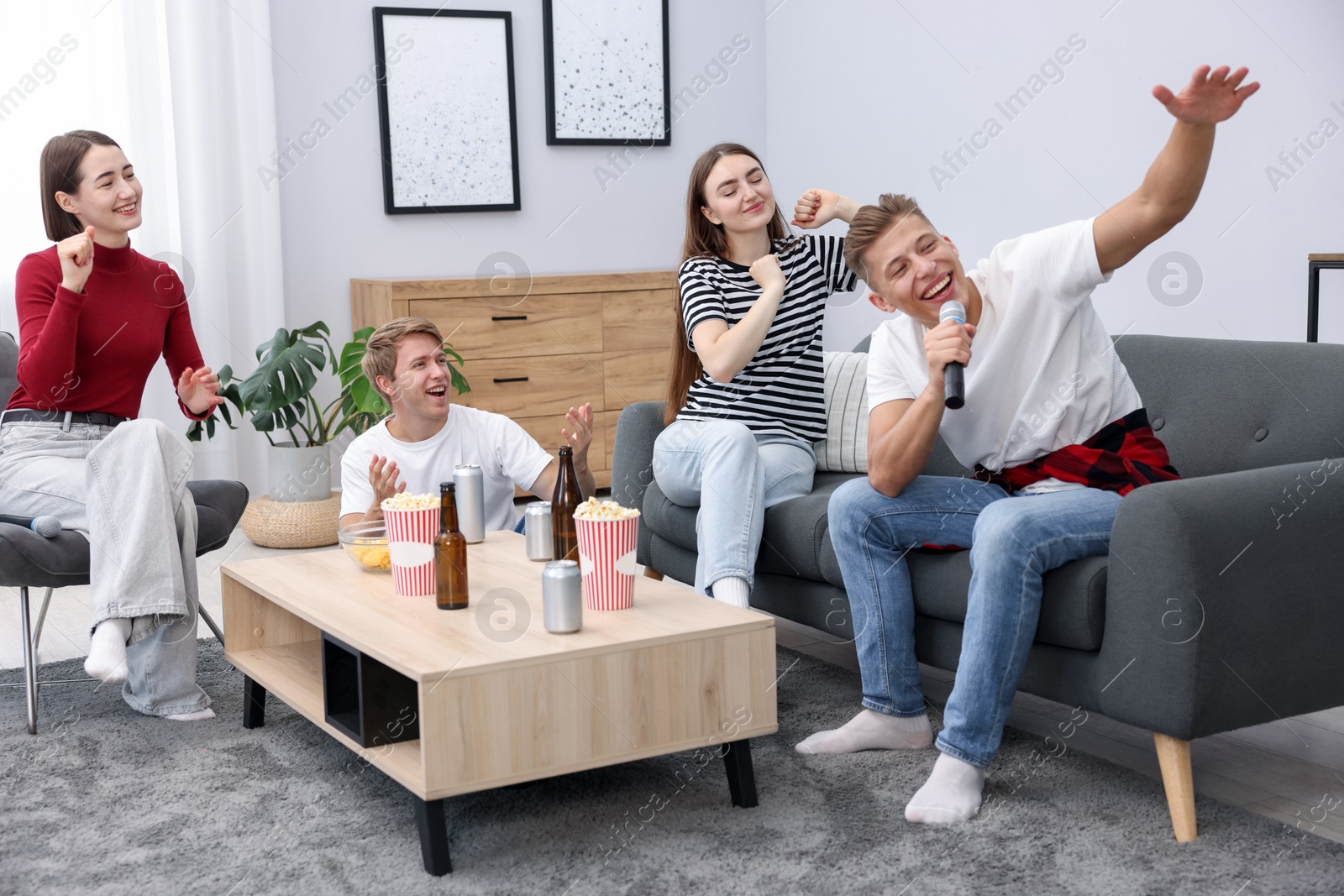 Photo of Young man singing karaoke with friends at home