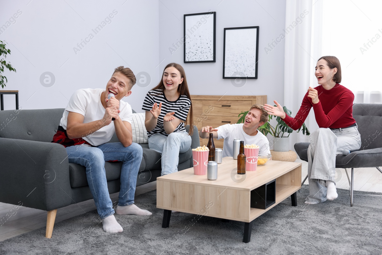 Photo of Young man singing karaoke with friends at home