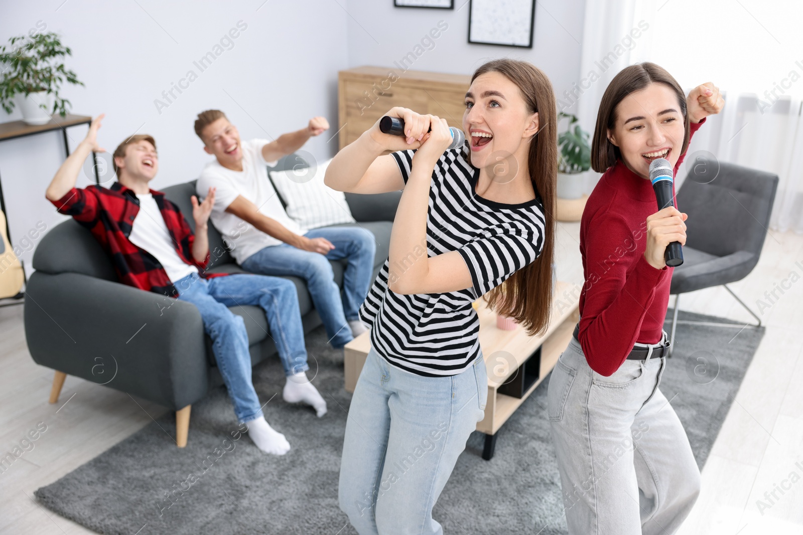 Photo of Young woman singing karaoke with friends at home, selective focus