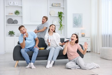 Photo of Group of friends singing karaoke at home