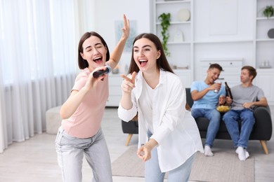 Photo of Young woman singing karaoke with friends at home, selective focus