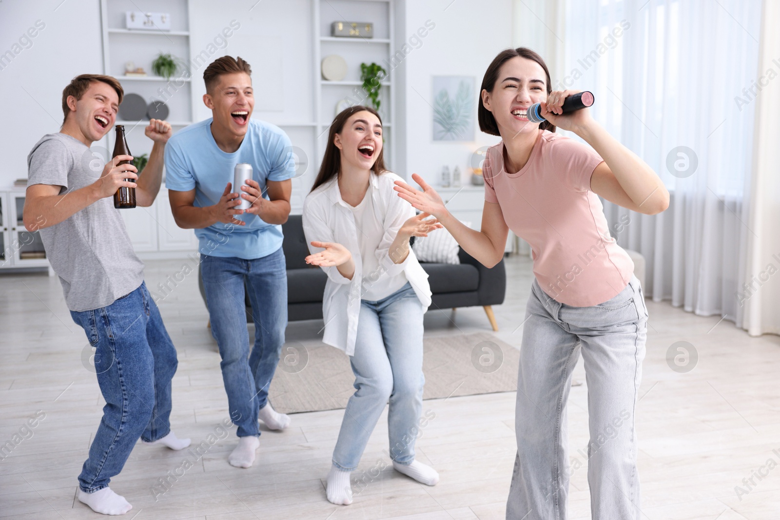 Photo of Young woman singing karaoke with friends at home