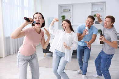 Photo of Young woman singing karaoke with friends at home