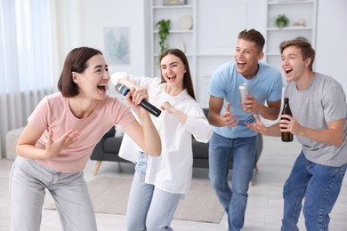Photo of Young woman singing karaoke with friends at home