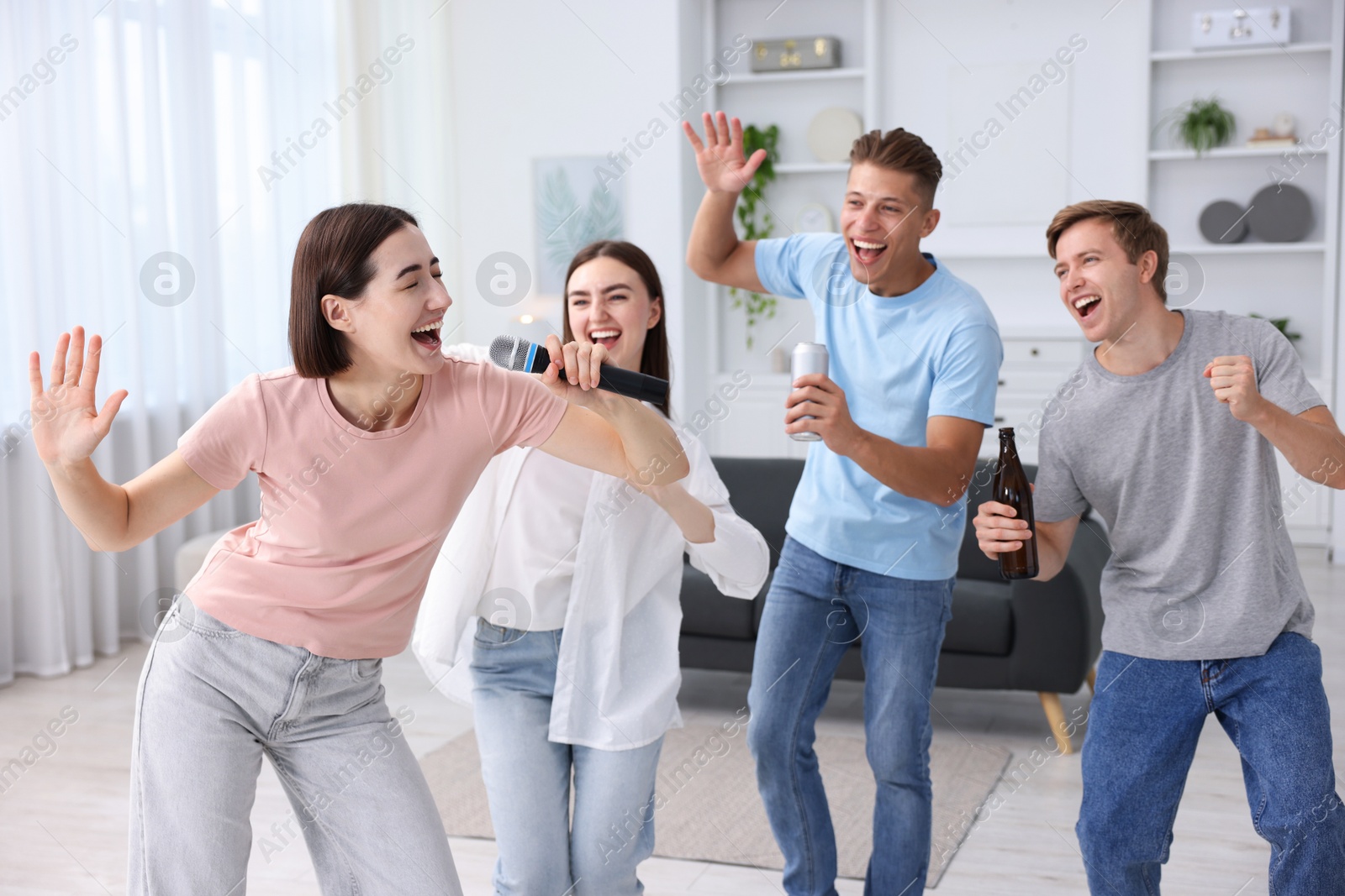 Photo of Young woman singing karaoke with friends at home