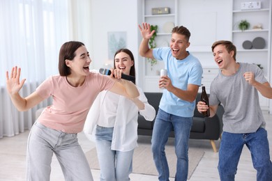 Photo of Young woman singing karaoke with friends at home