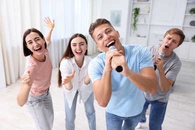 Photo of Group of friends singing karaoke at home, selective focus