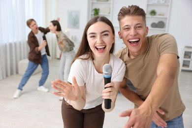 Photo of Group of friends singing karaoke at home, selective focus