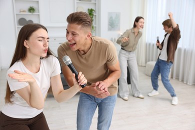 Photo of Group of friends singing karaoke at home, selective focus
