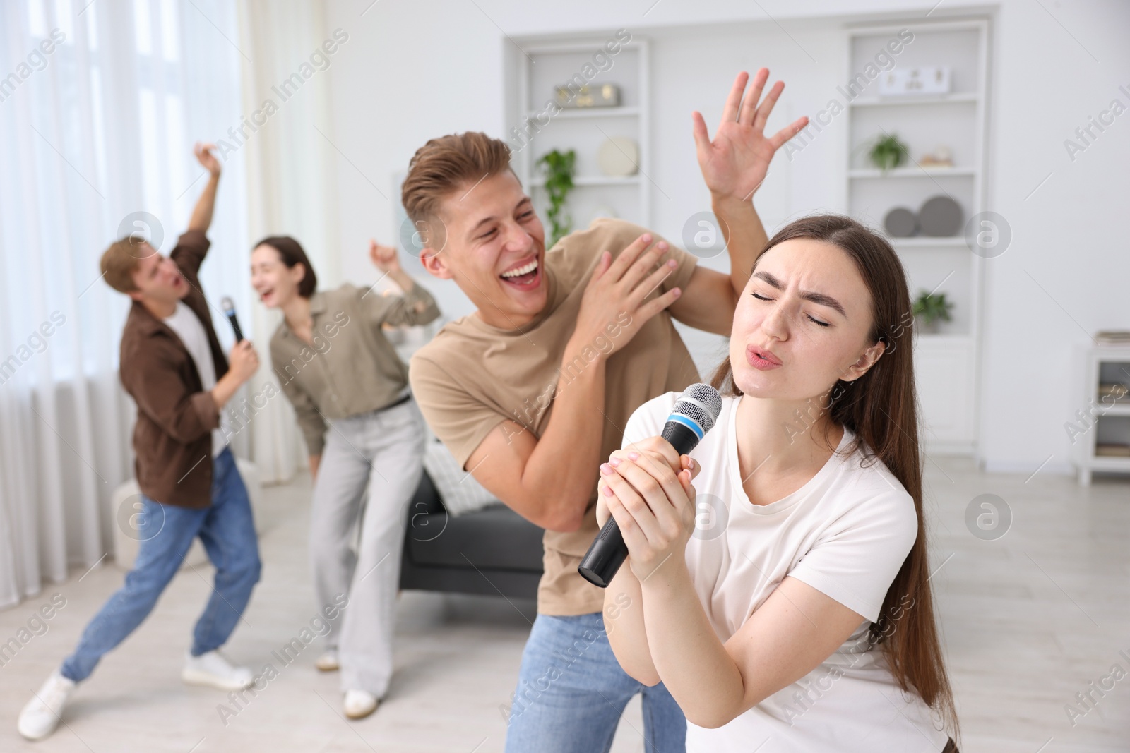 Photo of Group of friends singing karaoke at home, selective focus