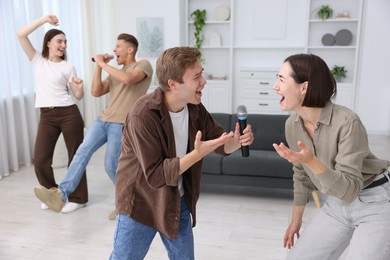 Photo of Group of friends singing karaoke at home, selective focus