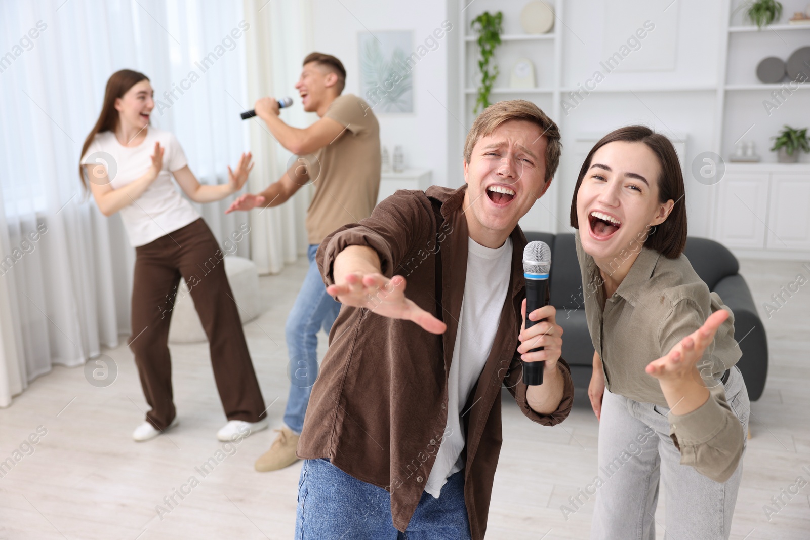 Photo of Group of friends singing karaoke at home, selective focus