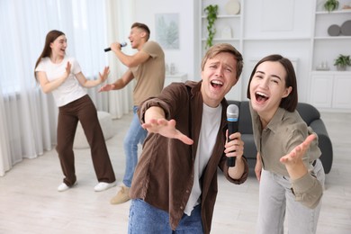 Photo of Group of friends singing karaoke at home, selective focus