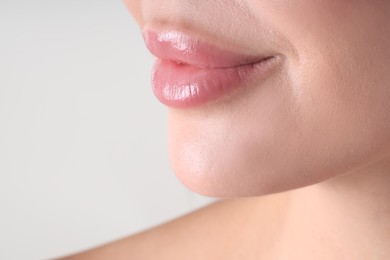 Photo of Woman with beautiful lips on light grey background, macro view. Space for text