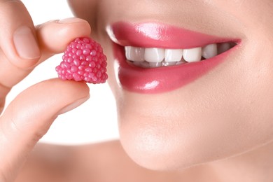 Photo of Woman with beautiful pink lipstick on her lips and raspberry candy against white background, closeup