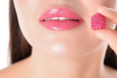 Photo of Woman with beautiful pink lipstick on her lips and raspberry candy against white background, closeup
