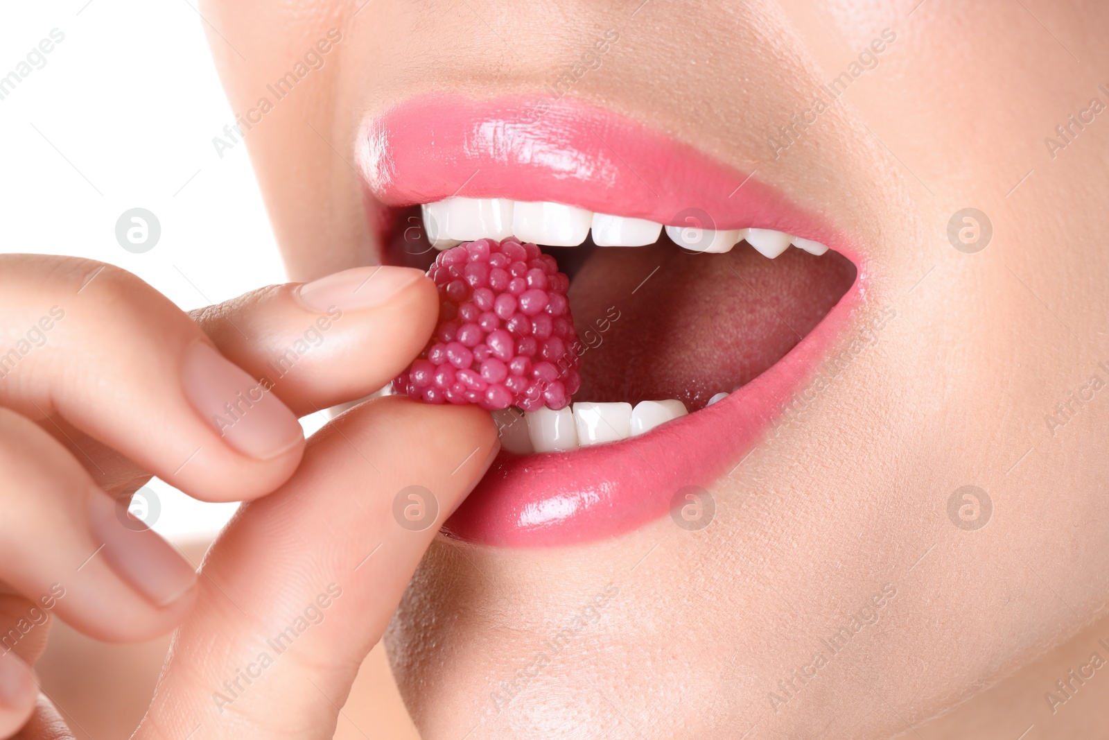 Photo of Woman with beautiful pink lipstick on her lips and raspberry candy against white background, closeup