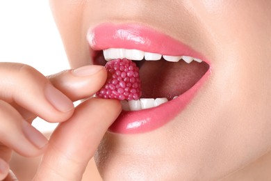 Photo of Woman with beautiful pink lipstick on her lips and raspberry candy against white background, closeup