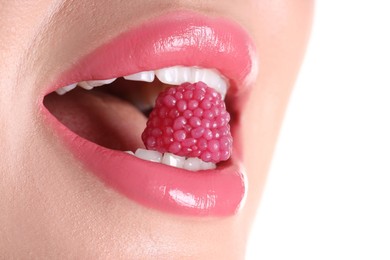 Photo of Woman with beautiful pink lipstick on her lips and raspberry candy against white background, closeup