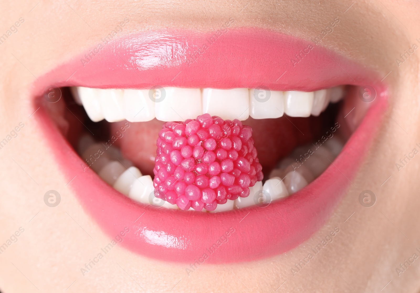 Photo of Woman with beautiful pink lipstick on her lips and raspberry candy, macro view