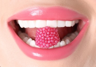 Photo of Woman with beautiful pink lipstick on her lips and raspberry candy, macro view