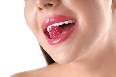 Photo of Woman with beautiful pink lipstick on her lips and raspberry candy against white background, closeup