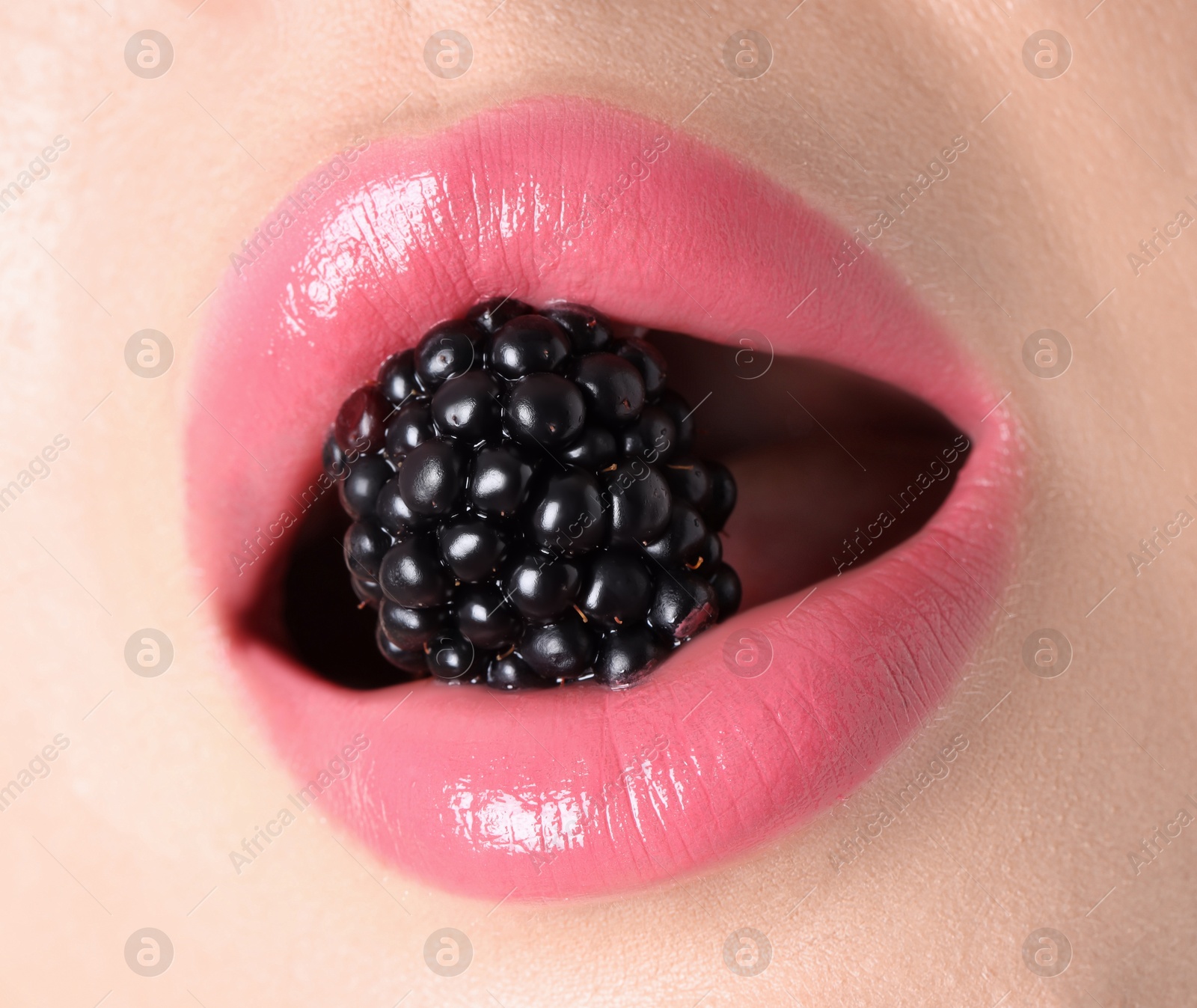 Photo of Woman with beautiful pink lipstick on her lips and blackberry, macro view