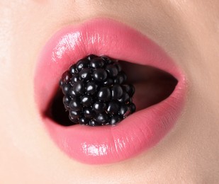 Photo of Woman with beautiful pink lipstick on her lips and blackberry, macro view