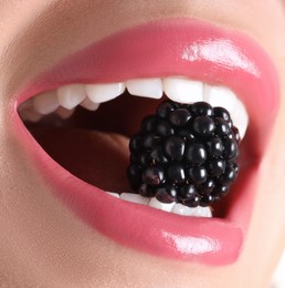 Photo of Woman with beautiful pink lipstick on her lips and blackberry, macro view