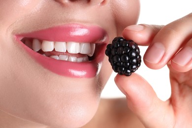 Photo of Woman with beautiful pink lipstick on her lips and blackberry against white background, closeup