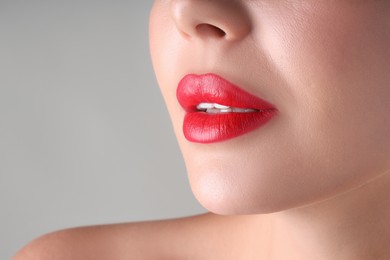 Photo of Woman with beautiful red lipstick on her lips against light grey background, macro view. Space for text