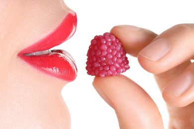 Photo of Woman with beautiful red lipstick on her lips and raspberry candy against white background, closeup