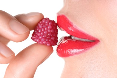 Photo of Woman with beautiful red lipstick on her lips and raspberry candy against white background, closeup
