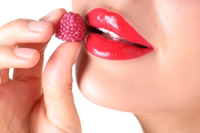 Photo of Woman with beautiful red lipstick on her lips and raspberry candy against white background, closeup