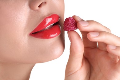 Photo of Woman with beautiful red lipstick on her lips and raspberry candy against white background, closeup