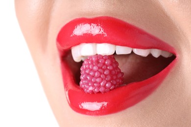 Photo of Woman with beautiful red lipstick on her lips and raspberry candy against white background, closeup