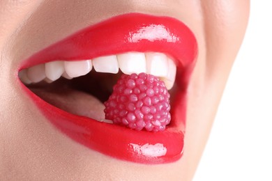 Photo of Woman with beautiful red lipstick on her lips and raspberry candy against white background, closeup