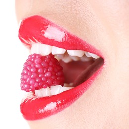 Photo of Woman with beautiful red lipstick on her lips and raspberry candy against white background, closeup