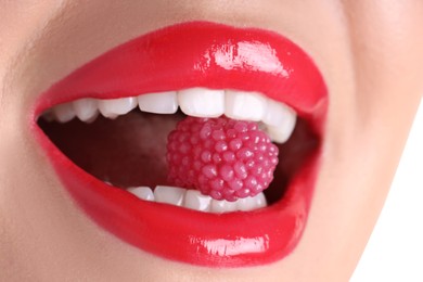 Photo of Woman with beautiful red lipstick on her lips and raspberry candy against white background, closeup