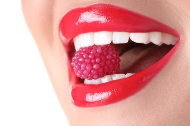 Photo of Woman with beautiful red lipstick on her lips and raspberry candy against white background, closeup