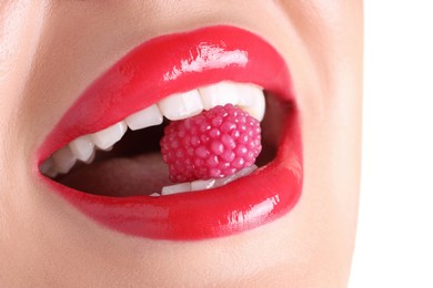 Photo of Woman with beautiful red lipstick on her lips and raspberry candy against white background, closeup