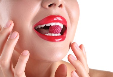Photo of Woman with beautiful red lipstick on her lips and raspberry candy against white background, closeup
