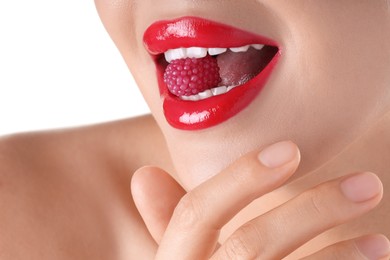 Photo of Woman with beautiful red lipstick on her lips and raspberry candy against white background, closeup