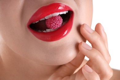Photo of Woman with beautiful red lipstick on her lips and raspberry candy against white background, closeup