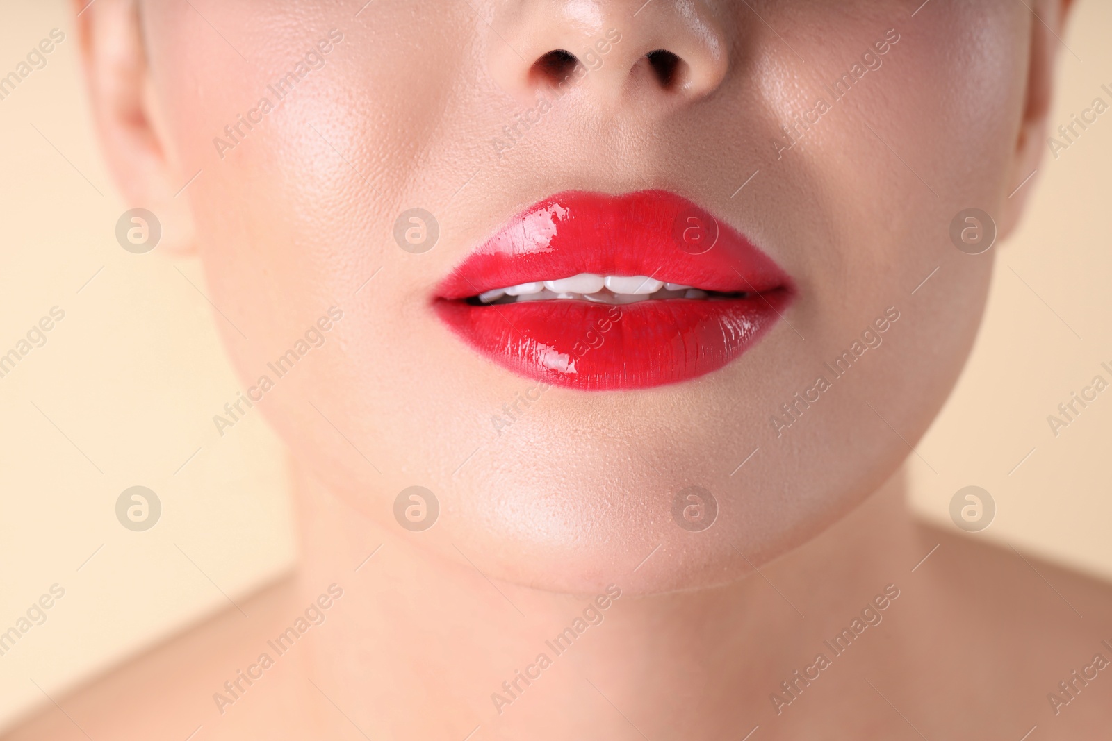 Photo of Woman with beautiful red lipstick on her lips against beige background, macro view