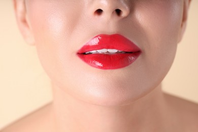 Photo of Woman with beautiful red lipstick on her lips against beige background, macro view