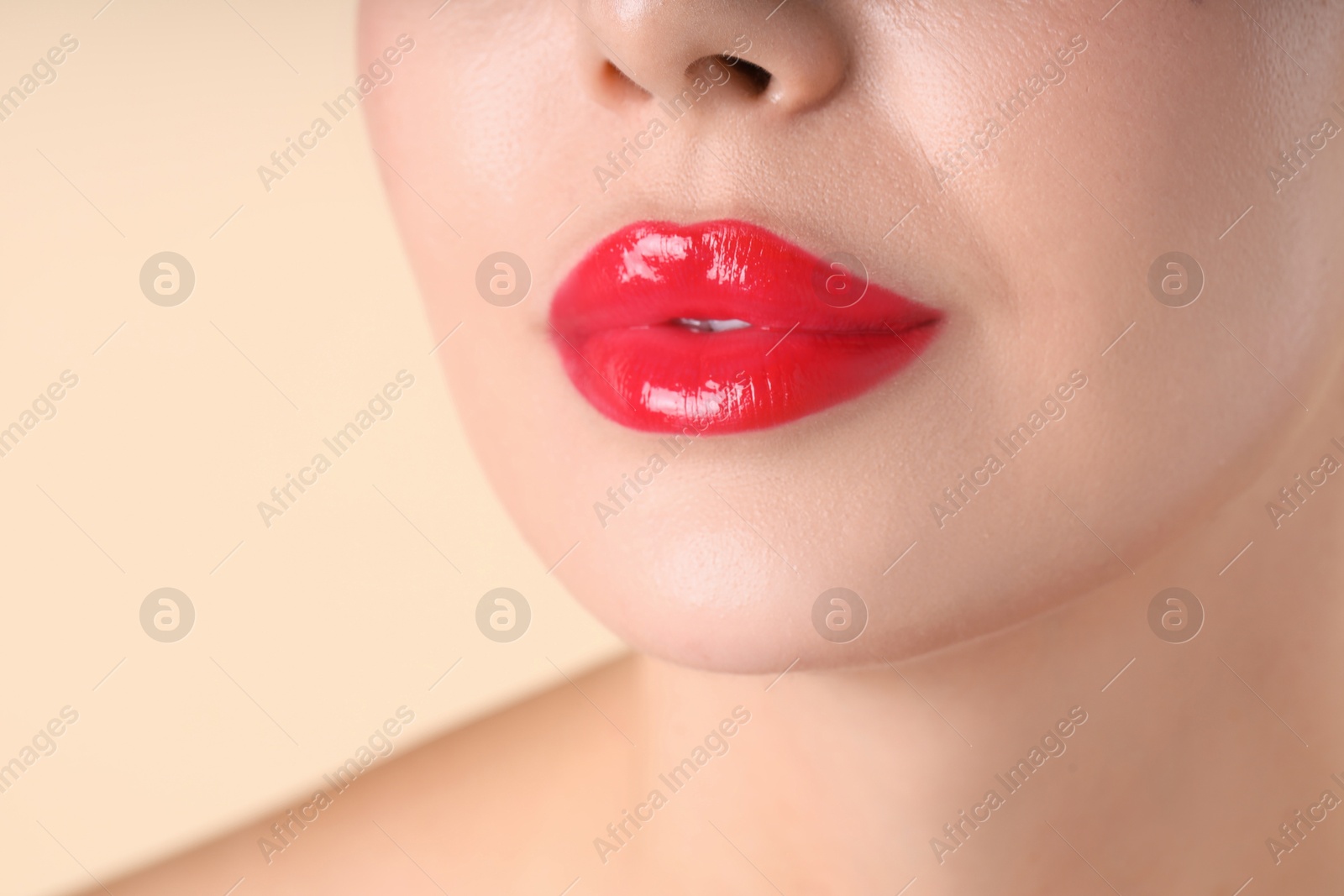Photo of Woman with beautiful red lipstick on her lips against beige background, macro view
