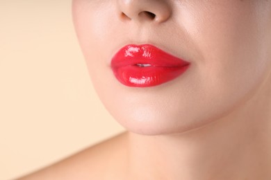 Photo of Woman with beautiful red lipstick on her lips against beige background, macro view