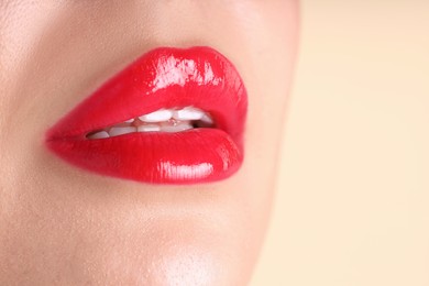Photo of Woman with beautiful red lipstick on her lips against beige background, macro view