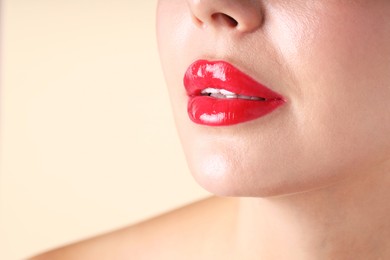 Photo of Woman with beautiful red lipstick on her lips against beige background, macro view. Space for text